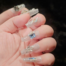 Load image into Gallery viewer, Hand model displaying Celestial Frost Long T Press-On Nails with a winter frost theme.