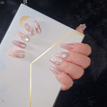 Load image into Gallery viewer, Close-up of pink press-on nails with white patterns and crystal embellishments.