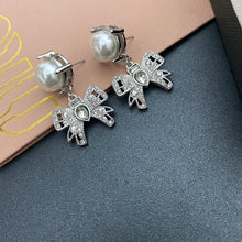 Load image into Gallery viewer, Platinum toned earrings with cute chic bows adorned with oversized resin pearls and white crystals
